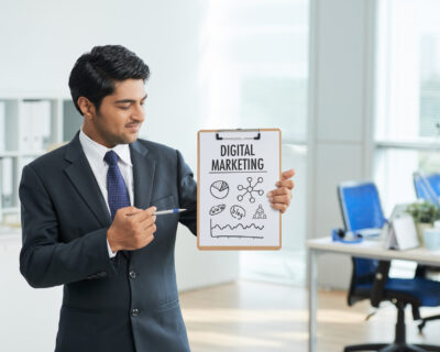 man-suit-standing-office-with-clipboard-pointing-poster-with-words